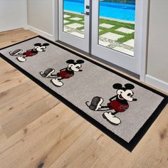 a mickey mouse door mat on the floor in front of a house with a pool