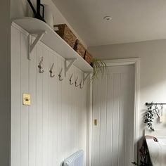 there is a coat rack on the wall in this hallway with white walls and wood flooring