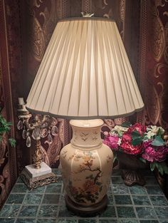 a lamp sitting on top of a table next to a vase with flowers in it