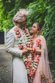 two people standing next to each other in front of trees