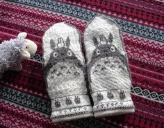 two knitted mittens sitting on top of a rug next to a stuffed animal