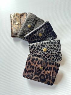 three pieces of animal print leather sitting on top of a white tablecloth with gold buttons