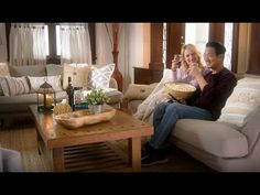 a man and woman sitting on a couch holding a glass of wine in their hands