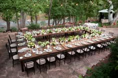 an outdoor dining table set up with white and green centerpieces on top of it