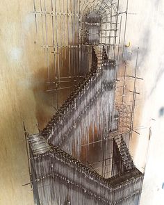 an artistic sculpture made out of wire on the floor in front of a wall with scaffolding around it