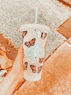 a hand holding a starbucks cup with butterflies on it