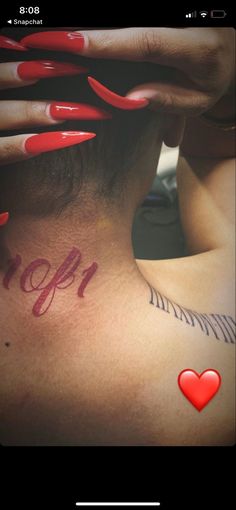 the back of a woman's head with red nails and tattoos on her neck