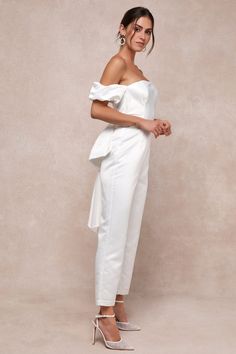 Any bride-to-be is guaranteed to start a trend with a voguish look like the Lulus Chic Vow White Satin Off-the-Shoulder Bow Jumpsuit! Sturdy woven satin shapes this stunning jumpsuit that starts with a princess-seamed bodice with supportive side boning, a sleek off-the-shoulder neckline (with hidden no-slip strips), and short puff sleeves with elastic at the shoulders and cuffs. The high, fitted waist tops slim-fitting, straight pant legs that finish at ankle-length hems. A dramatic, oversized b Spring Wedding Strapless Fitted Jumpsuit, Spring Wedding Fitted Strapless Jumpsuit, Feminine Fitted Jumpsuit For Formal Occasions, Feminine Fitted Jumpsuits And Rompers For Formal Occasions, White Strapless Jumpsuit For Summer Wedding, Elegant Off-shoulder Jumpsuits For Spring, Chic Strapless Jumpsuit For Wedding Guests, Elegant Off-shoulder Jumpsuits And Rompers For Spring, Summer Wedding Strapless Jumpsuit