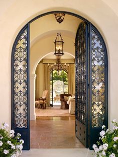 an open door leading to a living room and sitting area with flowers in the foreground