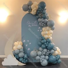 a blue and white balloon arch with stars, moon and clouds on the top for a baby's first birthday