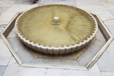 a decorative fountain on the ground in front of a manhole with a ball at the top