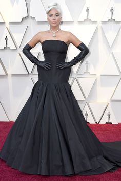 lady in black on the oscars red carpet wearing gloves and a gown with long sleeves