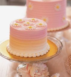 two pink and yellow cakes sitting on top of a table next to eachother