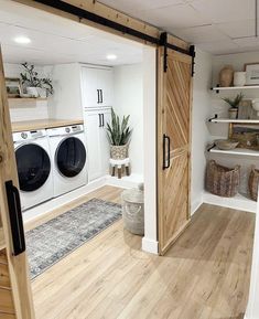 a washer and dryer in a room with wooden floors, white walls and open doors