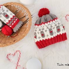 two knitted hats sitting on top of a white blanket next to candy canes