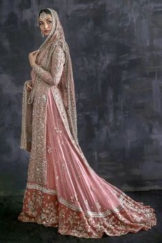 a woman in a pink and gold bridal gown standing with her hands on her hips