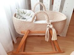 a wicker baby crib with a wooden handle and tassels on the handles