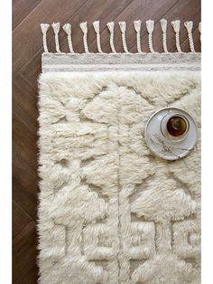 a white rug with tassels on it and a cup of coffee in the middle