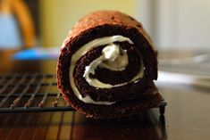 a chocolate roll with white frosting sitting on top of a cooling rack