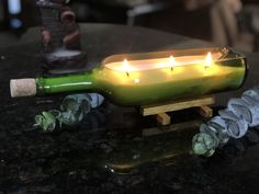 a lit candle in a wine bottle sitting on a table next to some rocks and candles