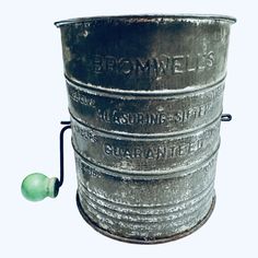 an old metal bucket with some green plastic balls in front of it and the words bromwells written on it