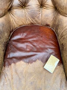 a brown leather chair with a piece of paper on the back of it's seat