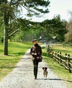 a woman walking her dog down a dirt road