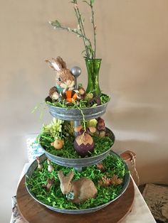 three tiered trays with plants and fake animals in them on top of a table