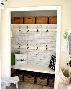 a white bench sitting under a window next to baskets and bins on the wall