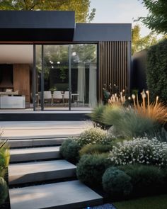 a modern house with large glass windows and steps leading up to the front yard area