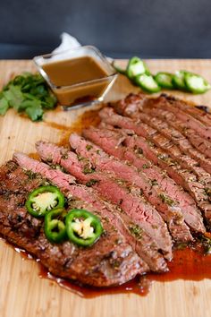 sliced steak with peppers and sauce on cutting board