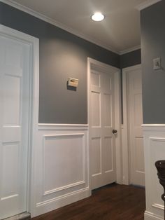 an empty room with white paneling and wood floors