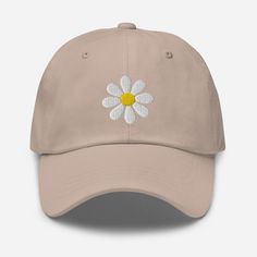 a tan baseball cap with a daisy embroidered on the front and back side, sitting against a white background