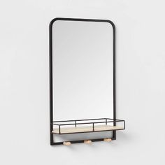 a mirror and shelf on the wall in front of a white wall with a black frame