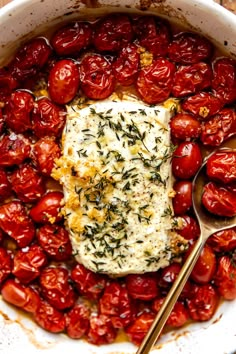 a pan filled with tomatoes, cheese and herbs