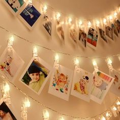 there are many pictures hanging on the wall with lights around them and string lights strung from the ceiling