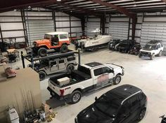 several vehicles are parked in a garage with two jeeps and one truck on the other side