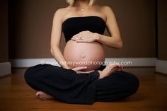 a pregnant woman sitting on the floor holding her belly