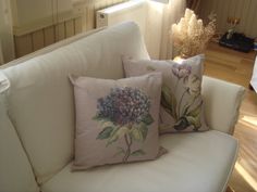 three pillows sitting on top of a white couch