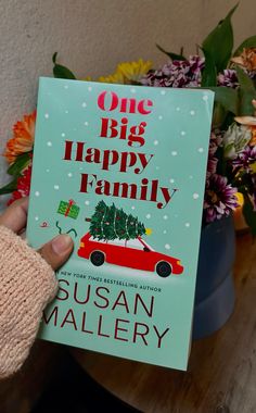 a person is holding up a book about the family christmas story, one big happy family