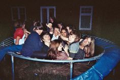 a group of people sitting on top of a trampoline in the dark at night