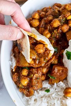 someone is holding a tortilla over rice in a bowl with chickpeas