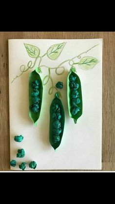 three peas are sitting on top of a piece of paper with green leaves and beads