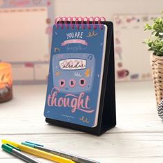 a notepad with the words you are beautiful on it next to two pens and a potted plant