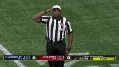 a referee is standing on the field with his hand to his head