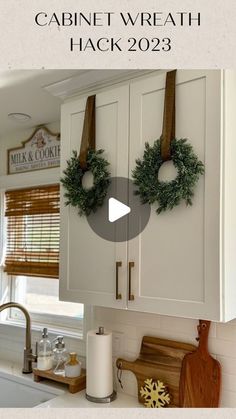 a kitchen with two wreaths hanging on the cabinets and a cutting board next to it