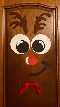 a wooden door decorated with paper cut out of reindeer's nose and antlers