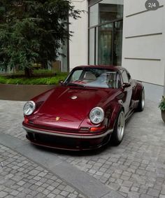 a red sports car parked in front of a building on a brick sidewalk next to potted plants