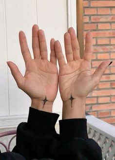 a woman with her hands in the air and two cross tattoos on her left wrist