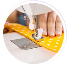 a woman is using a sewing machine to sew something on a yellow mat with white polka dots